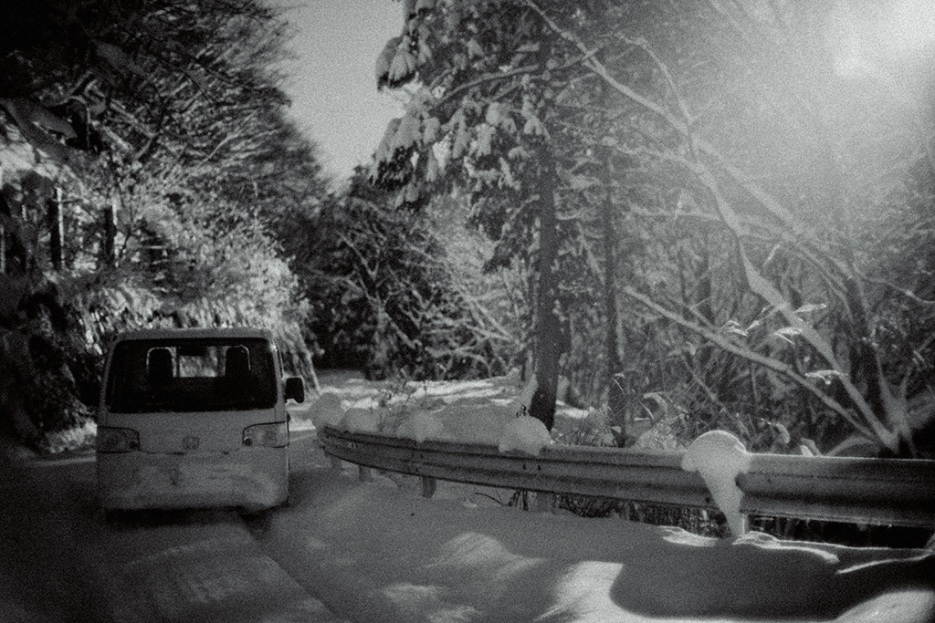 雪道の林道と軽トラック。