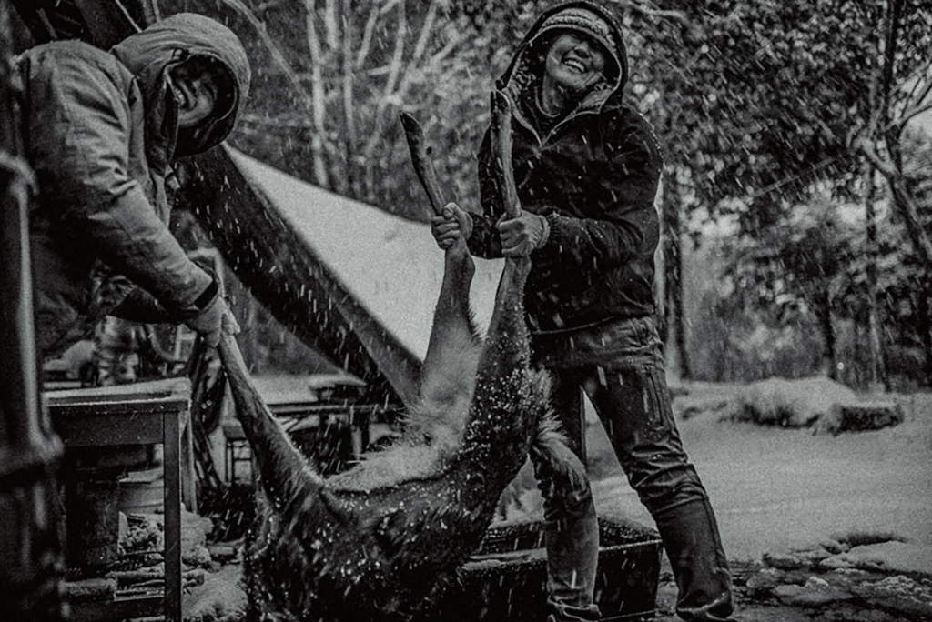 捕獲した鹿を笑顔で持ち上げる女性参加者2名