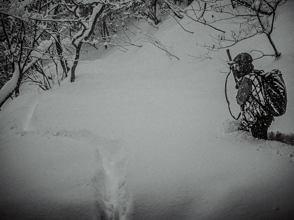 太腿まで積もる雪を掻き分け進む狩猟者松川