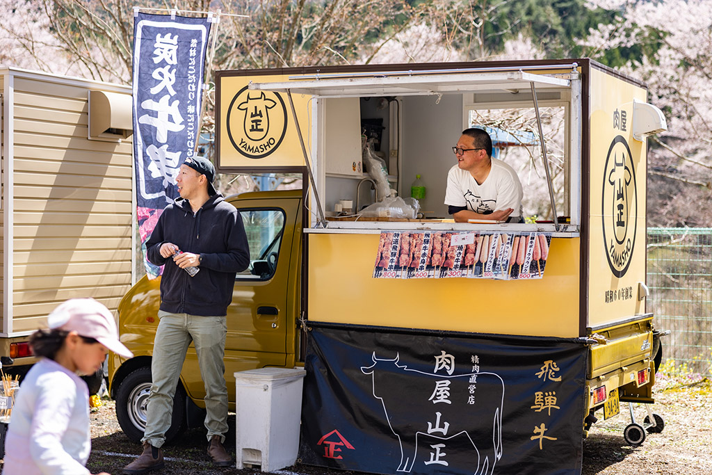 祭り会場を眺める店主とお客